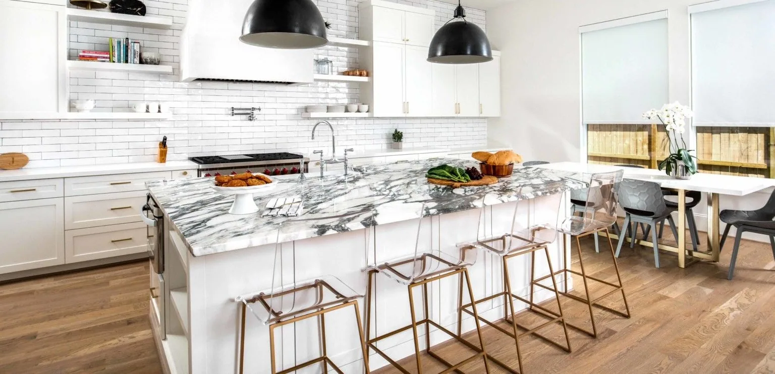 Cocina blanca con isla de mármol de veta gris marcada, mesada de piedra natural